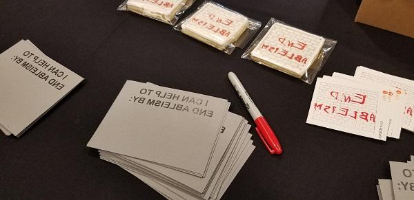 "End Ableism" printed on stickers, cookies, and notecards to fill in "I can help to End Ableism By" sitting on a table for the "End Ableism" event <span class="cc-gallery-credit"></span>